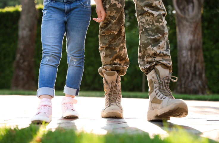 Person in military uniform walking with daughter at sunny park, closeup