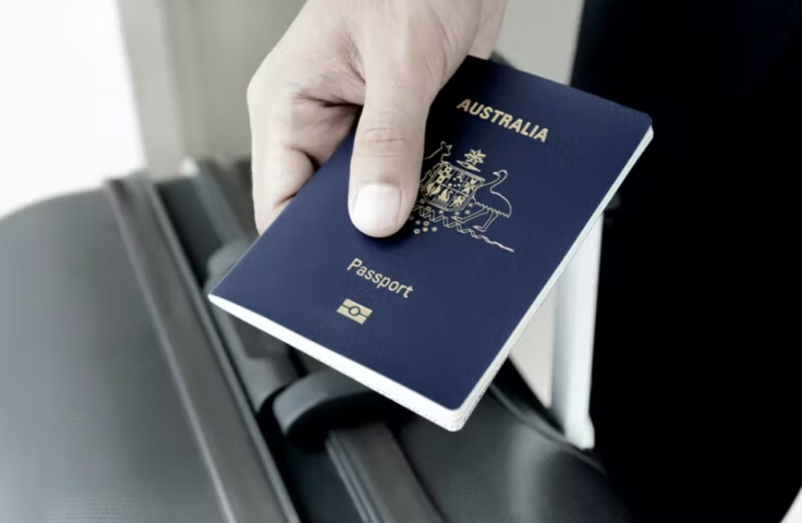A close up of a hand holding a passport on top of a suitcase. 